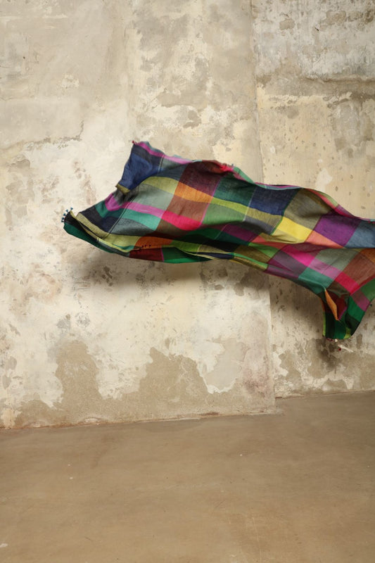 Model is wearing the Miraj 135 Cashmere Scarf by Injiri, handwoven from Himalayan cashmere with a multicolored Madras check and playful rounded borders, blending softness, warmth, and artisanal elegance.