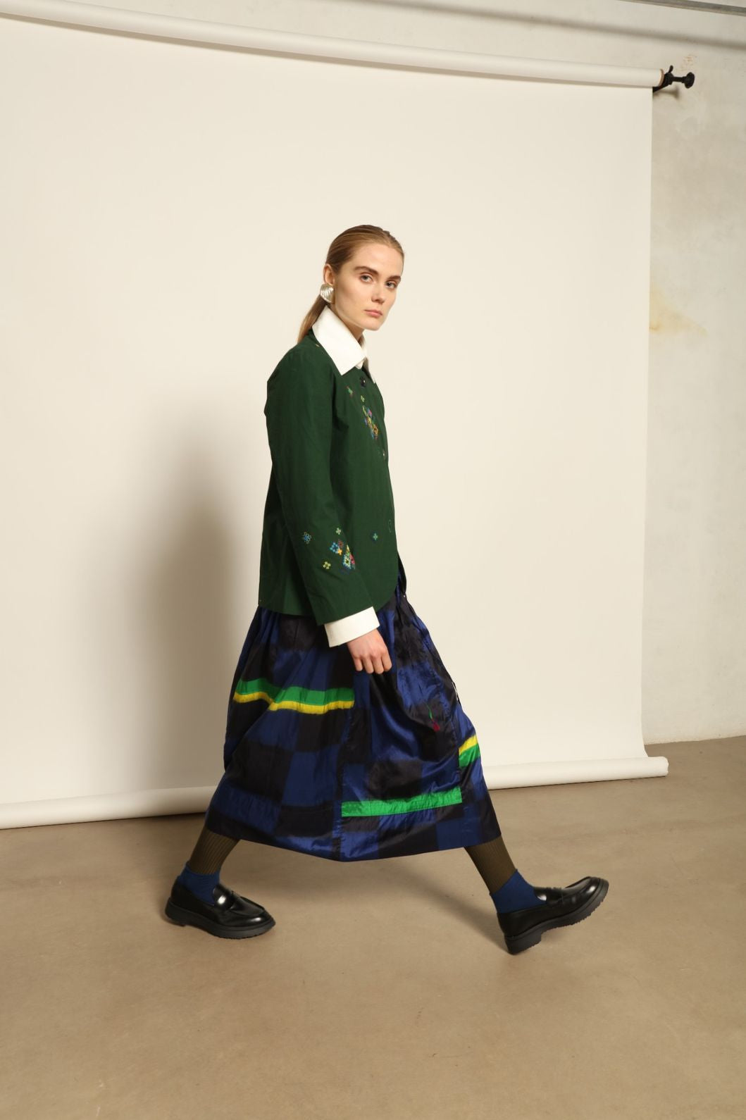 Model is wearing the Miraj 106 Cotton and Silk Skirt by Injiri, handcrafted in India with a blue check base and vibrant green and yellow rectangular motifs, blending heritage craftsmanship with bold contemporary design.