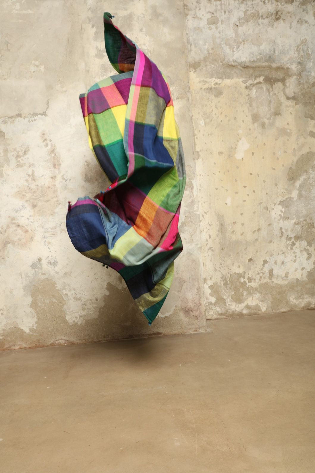 Model is wearing the Miraj 135 Cashmere Scarf by Injiri, handwoven from Himalayan cashmere with a multicolored Madras check and playful rounded borders, blending softness, warmth, and artisanal elegance.