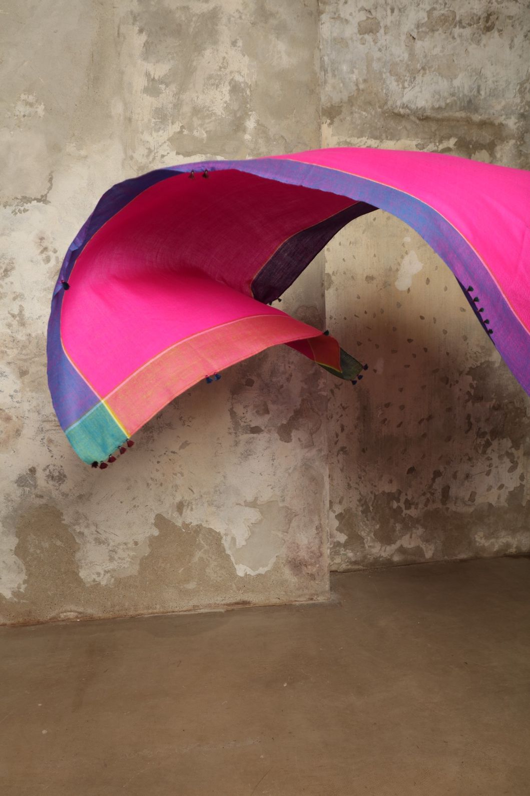 Model is wearing the Miraj 139 Cashmere Scarf by Injiri, handwoven from Himalayan cashmere with a soft pink base, teal and purple borders, and yellow accents, blending warmth, elegance, and artisanal craftsmanship.