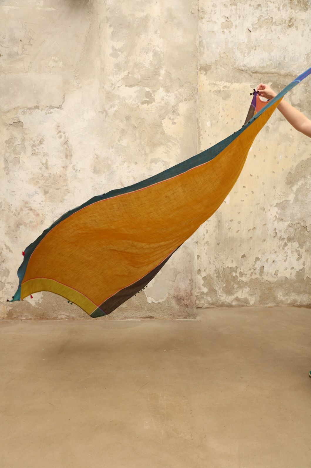 Model is wearing the Miraj 140 Cashmere Scarf by Injiri, handwoven from Kashmir cashmere with a vibrant ochre base and multicolor block borders, blending warmth, softness, and artisanal craftsmanship.