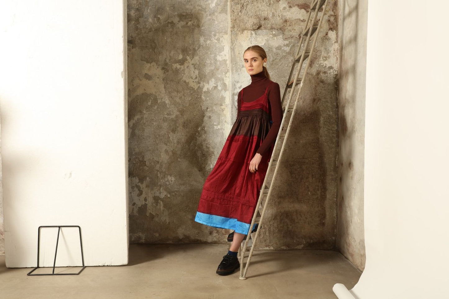 Model is wearing the Miraj 95 Silk and Cotton Slip Dress by Injiri, crafted in red and brown cotton with silk accents and a bold blue border, combining lightness, color, and refined craftsmanship.