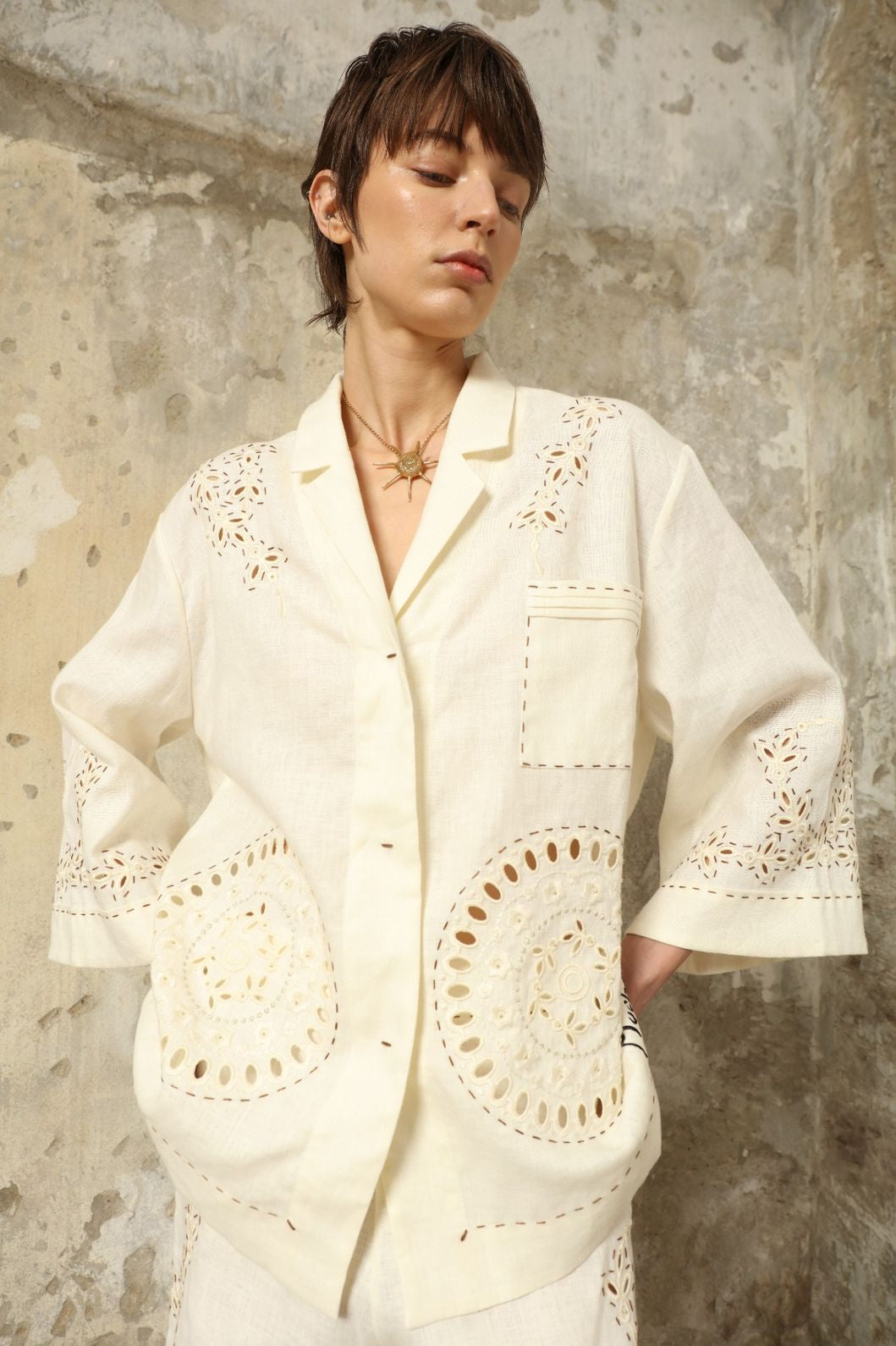 Model is wearing the My Sleeping Gypsy Sarah Suit, a handcrafted ivory linen set with high-waisted shorts, relaxed jacket, intricate embroidery, and 24-carat bead accents, from the House of Nomad Stories selection.