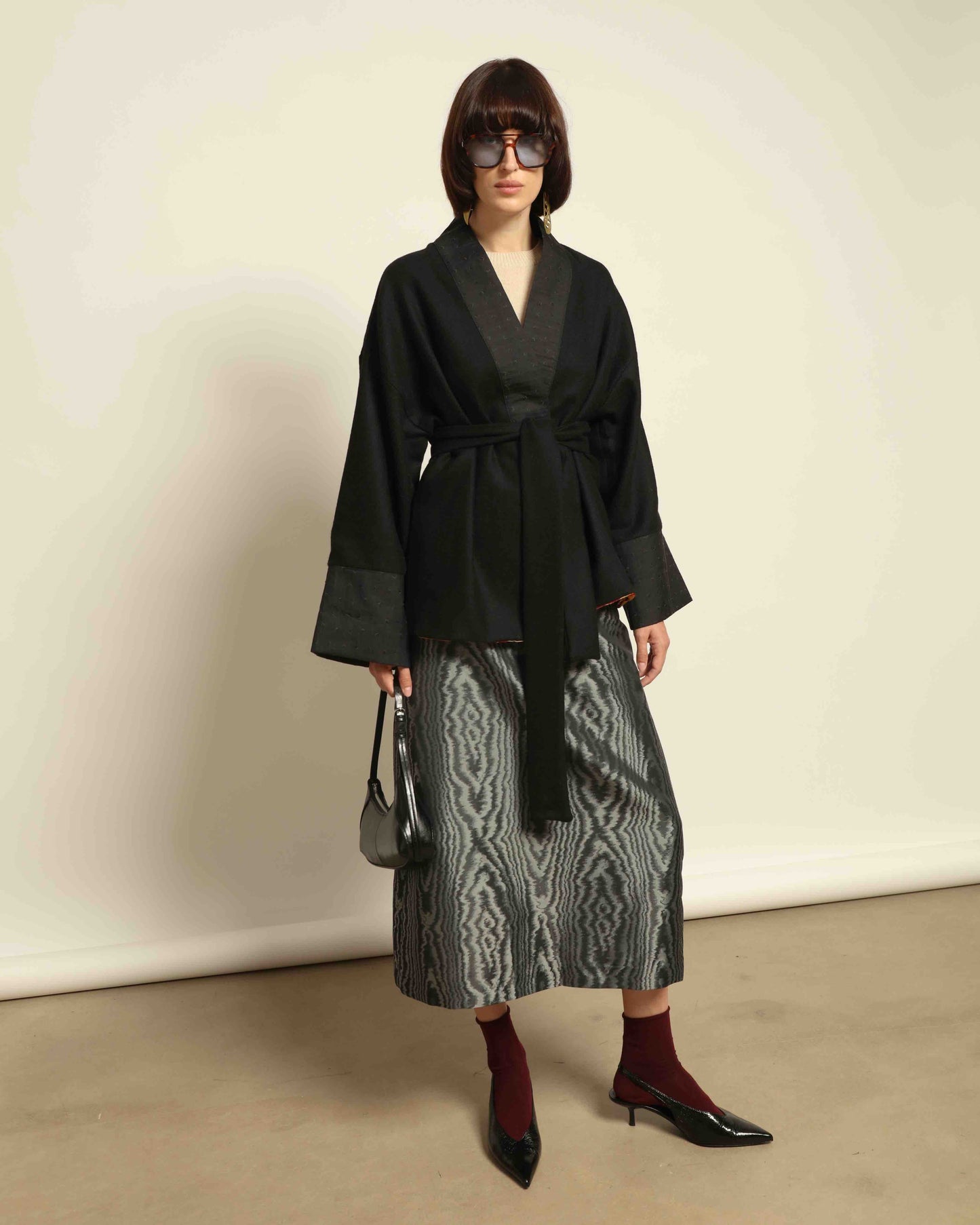 The model is wearing the Obidi Midnight Kantha Jacket in pure black, made of wool with a silk collar and Kantha silk lining, a timeless and versatile piece.