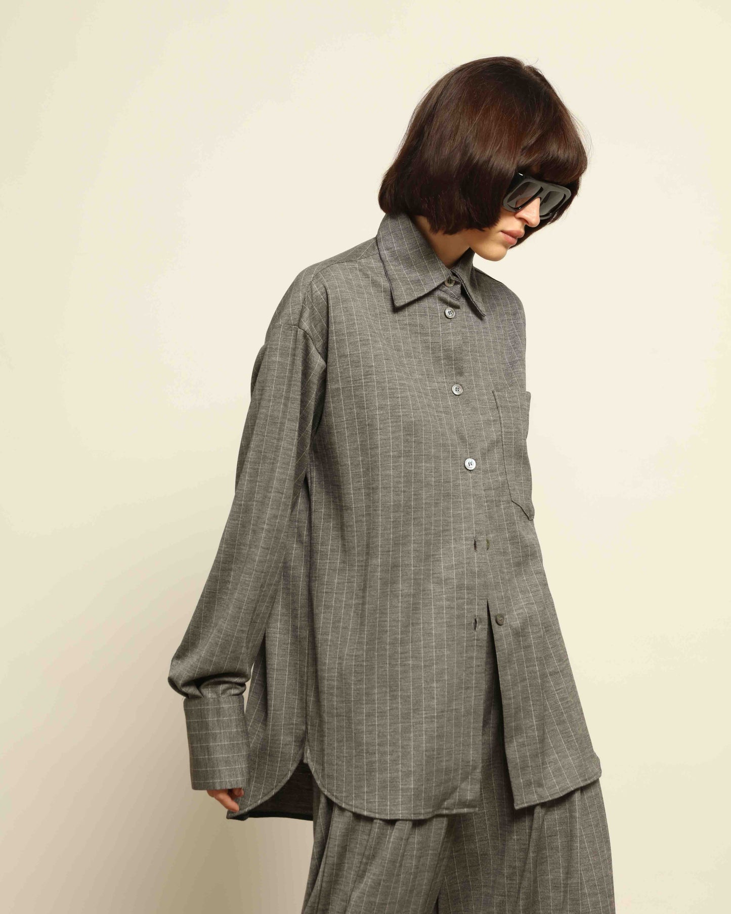 Model is wearing the Oscar Pinstriped Grey Jersey Shirt by House of Woven Stories, crafted in Italy from a merino wool and silk blend with subtle grey stripes and a tailored silhouette.