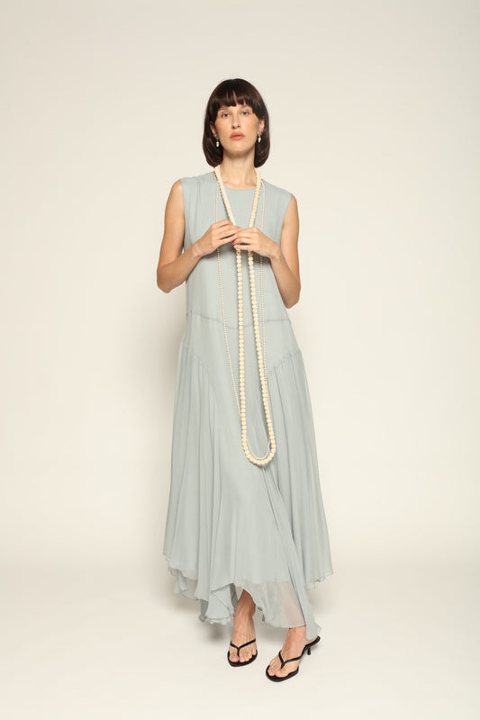 Model wearing a blue Panelled Dress by Abadia from the House of Nomad Stories collection, featuring a sleeveless midi silhouette, round neckline, and structured waist panel detailing with a minimal elegant finish.