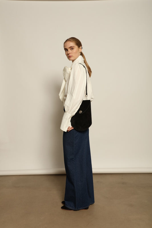 Model is wearing Le Pantalon Peacock in Brut Vintage by Happy Haus, high-waisted wide-leg cotton trousers with double-stitched back pockets and delicate embroidered peacock detail, combining timeless elegance with relaxed sophistication.