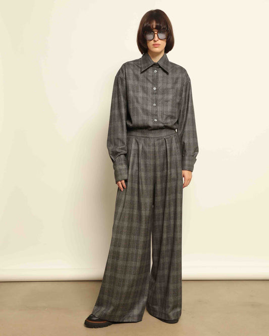 Model is wearing the Parigi Grey Check Trousers by House of Woven Stories, featuring a refined grey check pattern and a tailored silhouette, handcrafted in Piedmont, Italy.