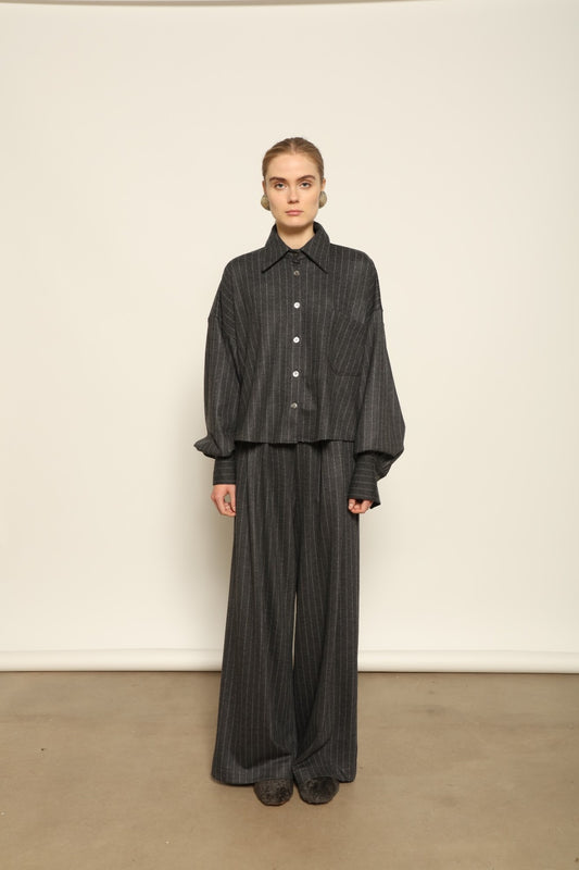 Model wearing Parigi Trousers in Double Jersey Striped Grey and White by House of Woven Stories, part of the curated selection, made in Italy from 100% Merino wool, featuring soft double jersey texture and elegant striped design for refined comfort and timeless style.