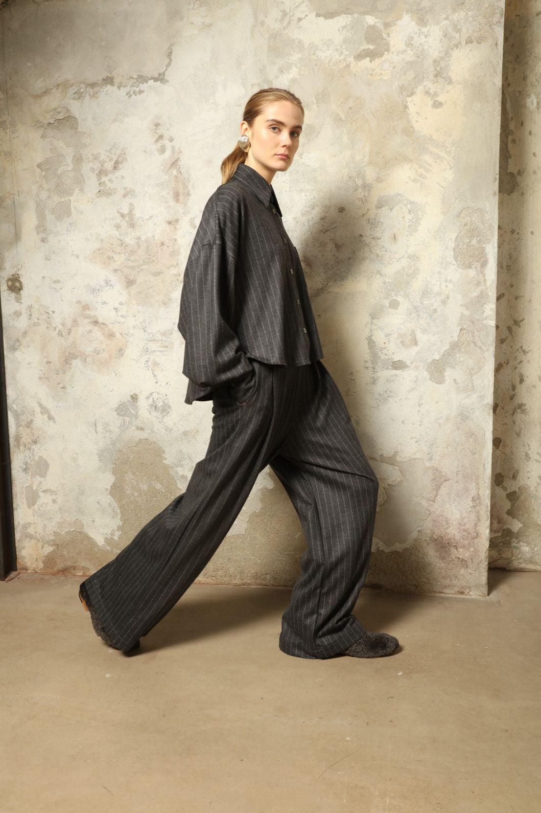 Model wearing Parigi Trousers in Double Jersey Striped Grey and White by House of Woven Stories, part of the curated selection, made in Italy from 100% Merino wool, featuring soft double jersey texture and elegant striped design for refined comfort and timeless style.