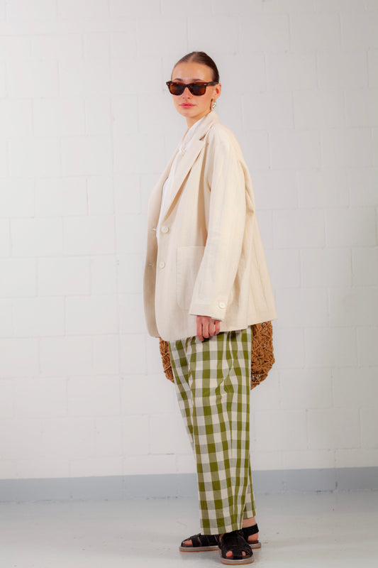 Model is wearing the Pine Checked Trousers by Balia 8.22, handcrafted in Italy from cotton and linen, featuring a relaxed straight-leg fit with pine green and white check pattern.