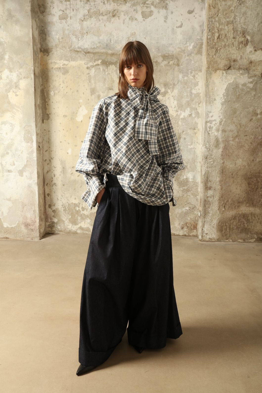 Model is wearing the Regula Maxi Check Popeline Cotton Blouse by House of Woven Stories, crafted from crisp poplin cotton in an oversized check pattern with a waist tie and buttoned cuffs.