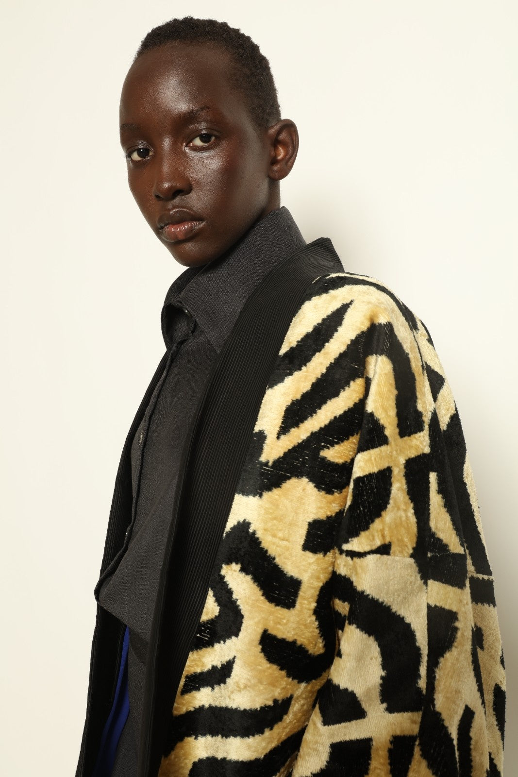 Model is wearing the Serai Ikat Velvet Jacket by Aleksandra Viktor, part of House of Woven Stories collection, handwoven Uzbek ikat velvet jacket with black collar, flowing silhouette, and vibrant blue lining