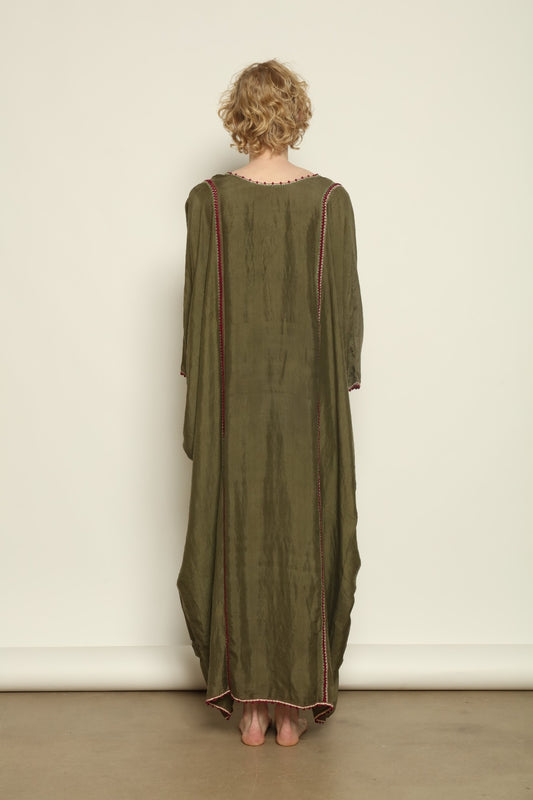 Model is wearing the Thea Olive Silk Dress by Supernaturae in soft olive-toned handwoven silk from Murshidabad, featuring a relaxed flowing silhouette and elegant open back. This sustainable ethical fashion dress is crafted using traditional weaving techniques and natural fibers, designed for everyday wear with a breathable, lightweight drape.