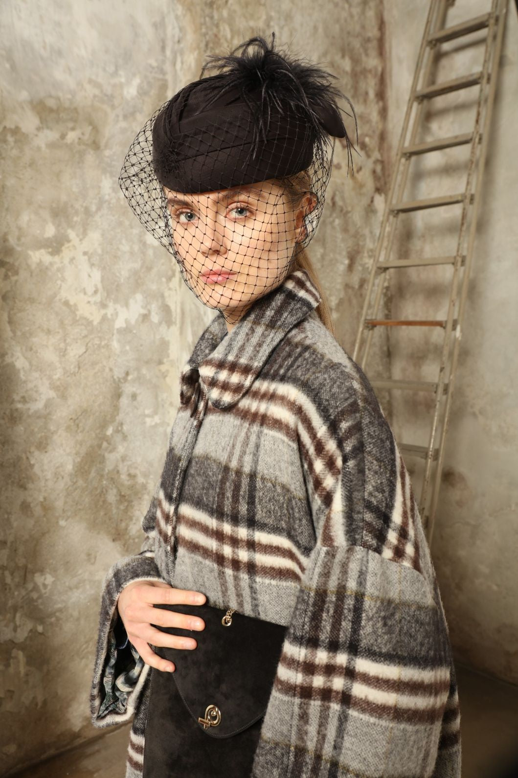 Model is wearing the Tiflis Checked Coat by House of Woven Stories, crafted from a soft wool blend with muted grey and brown checks, featuring an oversized silhouette, wide sleeves, and structured collar for timeless elegance.