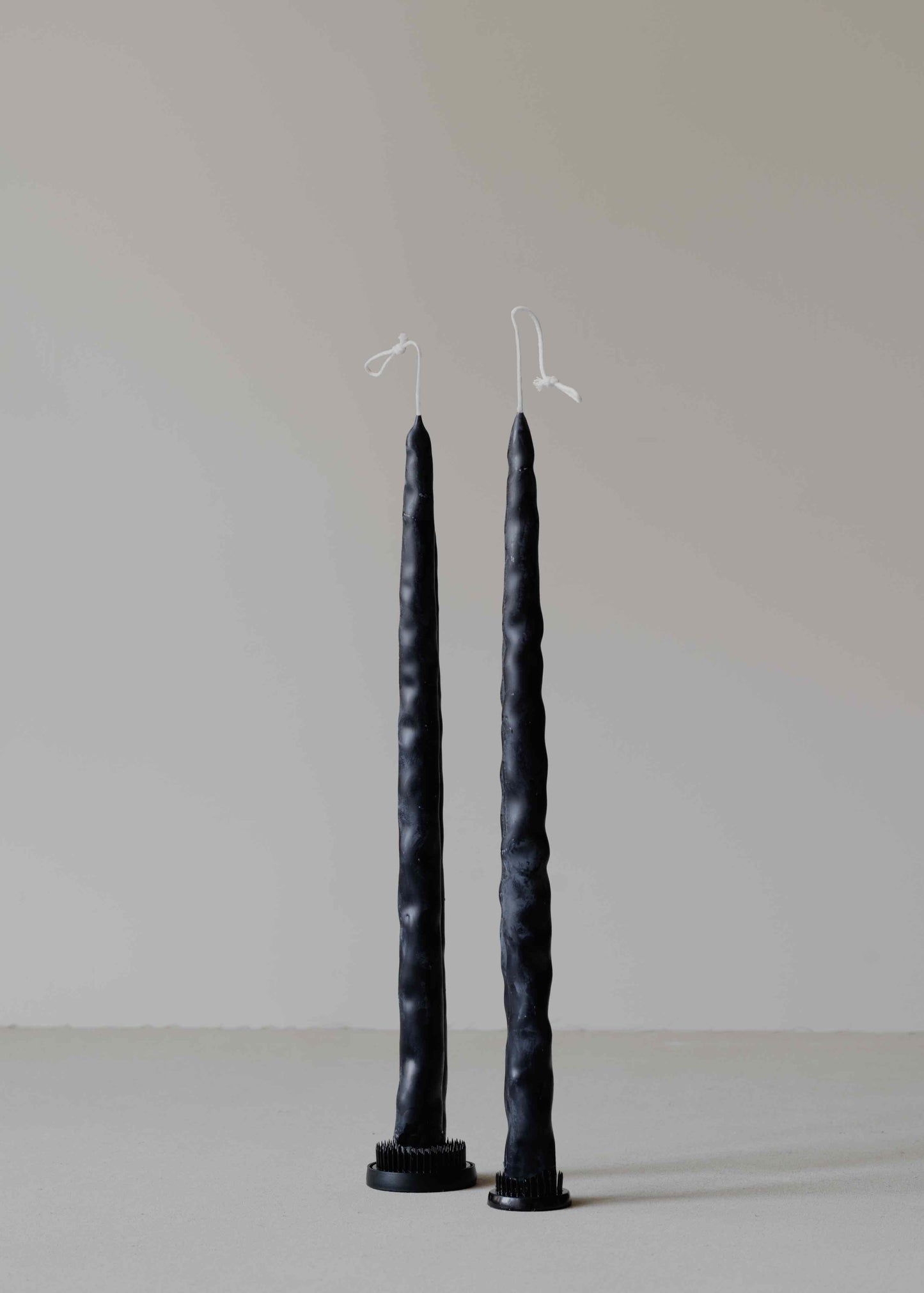 Twig Pair in Black by Oberflacht, part of the House of Woven Stories selection, handcrafted from beeswax and paraffin with slender shape, deep black hue, and subtle variations in form and texture.