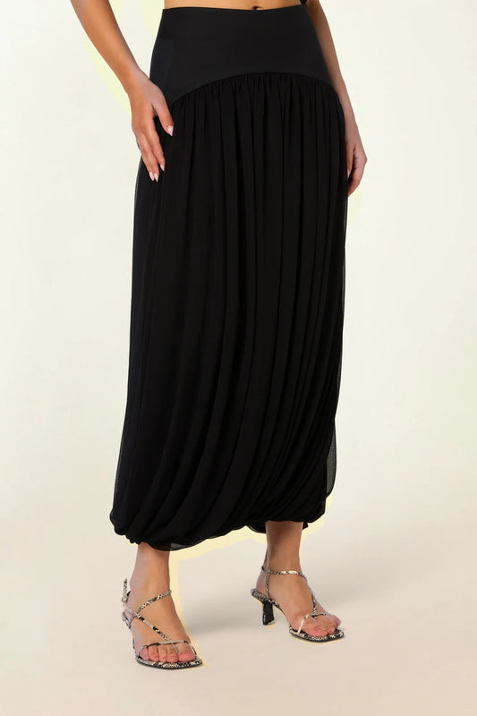 Model wearing the Twisted Suri Skirt in Black by Abadia from the House of Nomad Stories collection, featuring a curved waistband, mid-waist fit, and an elegant draped silhouette with fluid movement.