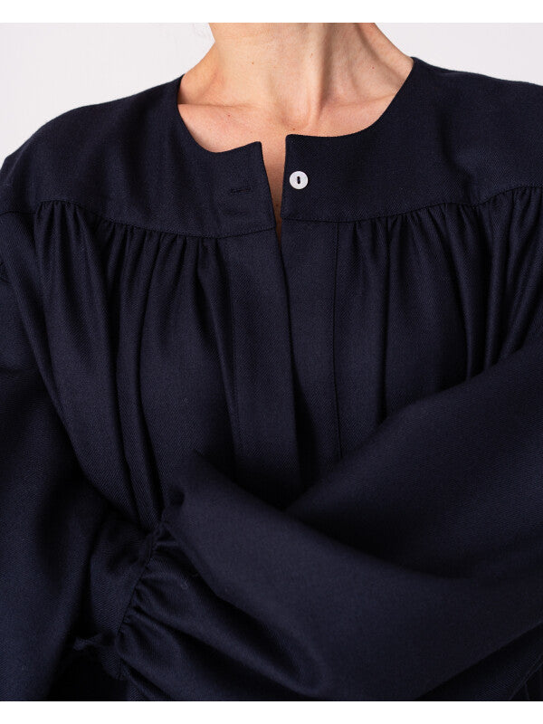 Model is wearing the Winter Calla Dress by Les Vacances d’Irina, a full-length navy merino wool dress with drop-waist silhouette, billowy sleeves, and bow cuffs, handmade in Bucharest and available at House of Woven Stories.