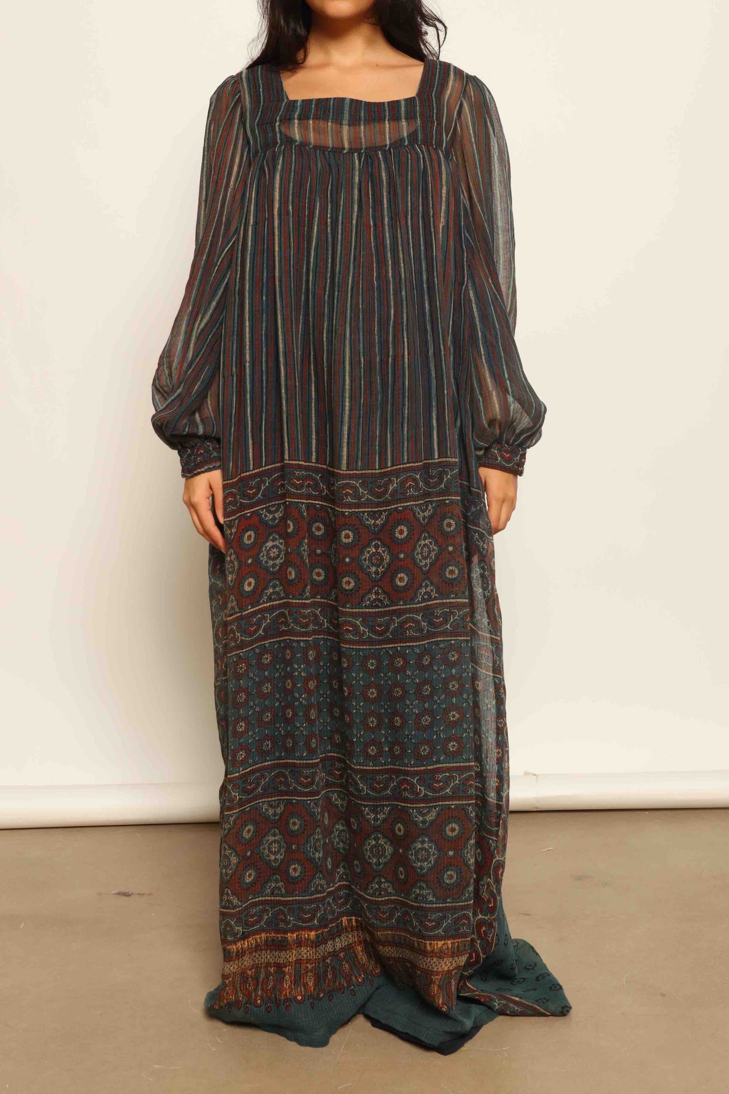 Model is wearing the Woodstock Dark silk dress by House Of Woven Stories, handcrafted in Italy from re-wearable sari fabric, featuring sheer sleeves, handprinted details, and a flowing silhouette.