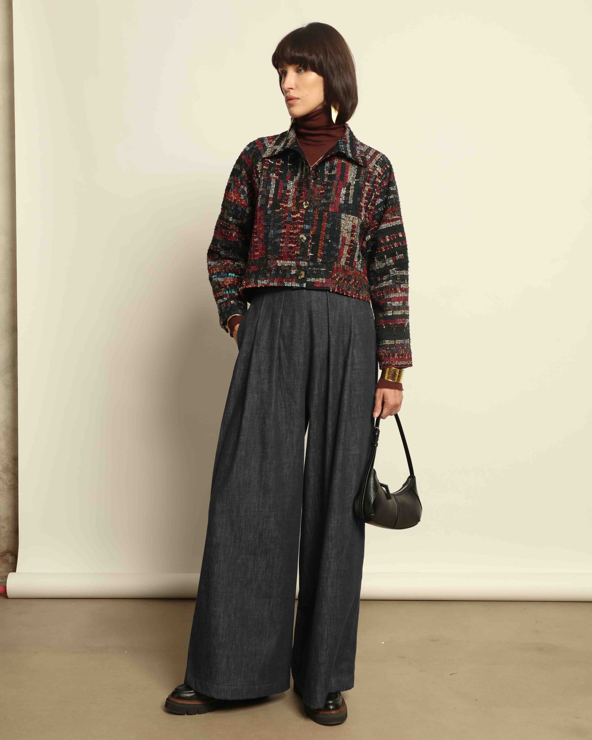 Model is wearing the Rewoven Hand-loomed Bomber by Paiwand, an upcycled unisex jacket crafted from handwoven organic cotton off-cuts with unique color and design variations.