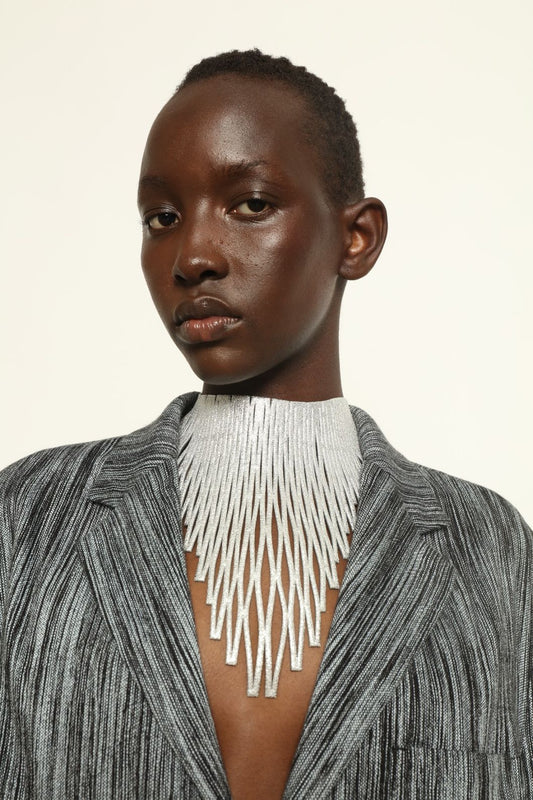 Model is wearing Luminous Silver Leather Necklace by SO-LE STUDIO, handcrafted from upcycled Italian leather with slender diamond-shaped elements forming a fluid, radiant cascade around the neckline, part of the curated selection at House of Woven Stories, combining lightweight elegance with sculptural design.