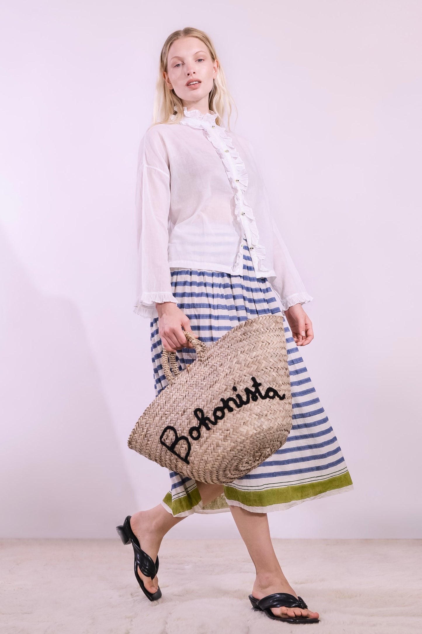Model wearing a long pleated pure cotton skirt with indigo and off-white stripes, elastic waistband, and pistachio hem. Handcrafted in India by Injiri.