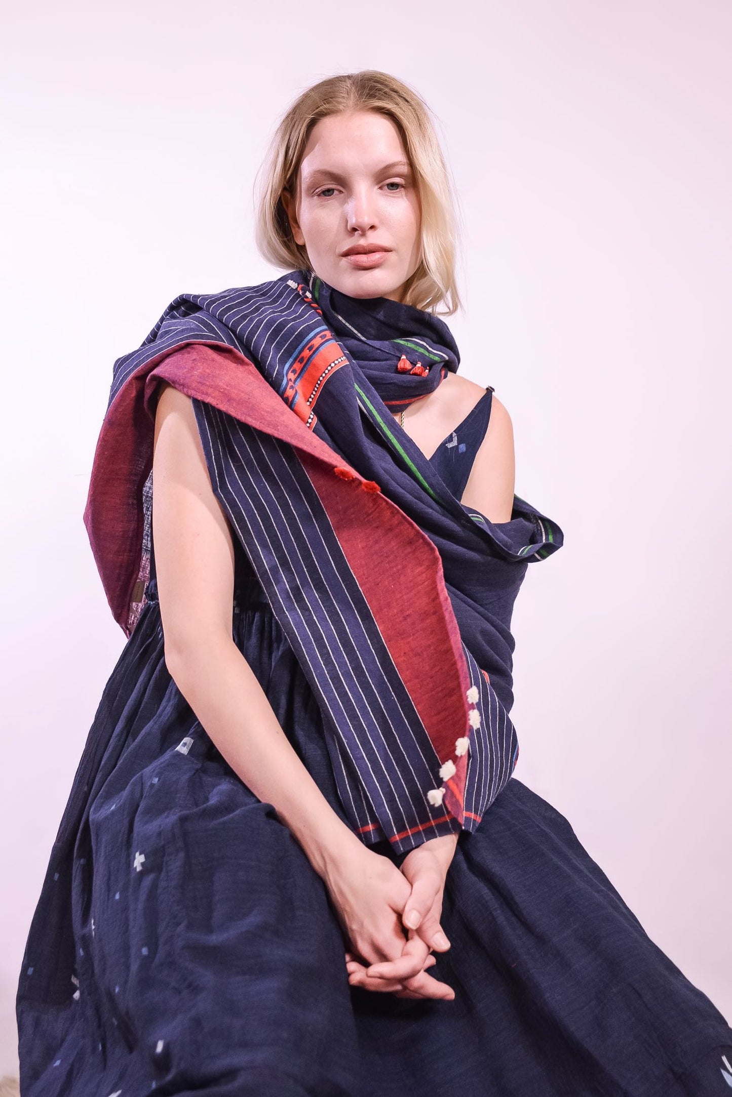 Model wearing pure cotton scarf by Injiri – handloomed unisex accessory in natural indigo with red and white woven details, crafted from organic cotton and finished with tassels. Ethically handmade in India