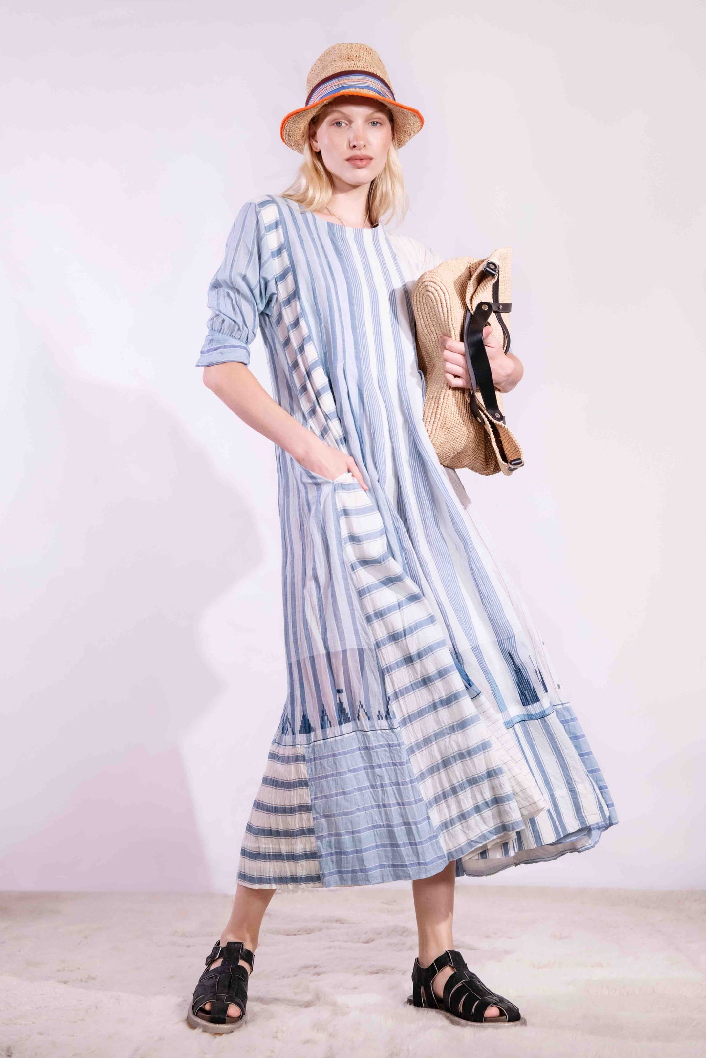 Woven wearing handcrafted pure cotton dress by Injiri in white with blue patterns and delicate embroidery, featuring short sleeves, side pockets, and a relaxed, airy silhouette. Available at House of Woven Stories.