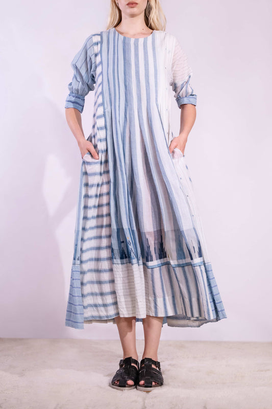 Woven wearing handcrafted pure cotton dress by Injiri in white with blue patterns and delicate embroidery, featuring short sleeves, side pockets, and a relaxed, airy silhouette. Available at House of Woven Stories.