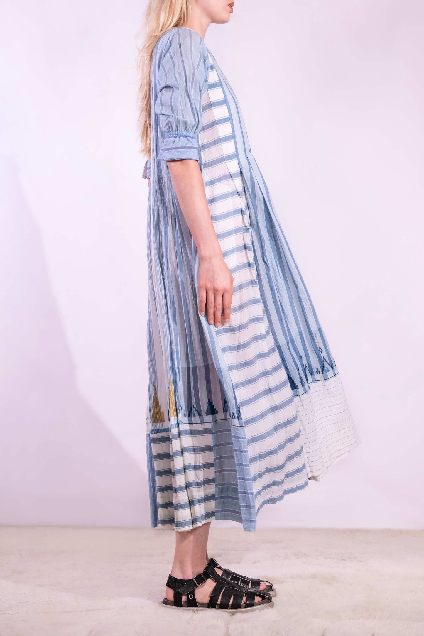 Woven wearing handcrafted pure cotton dress by Injiri in white with blue patterns and delicate embroidery, featuring short sleeves, side pockets, and a relaxed, airy silhouette. Available at House of Woven Stories.