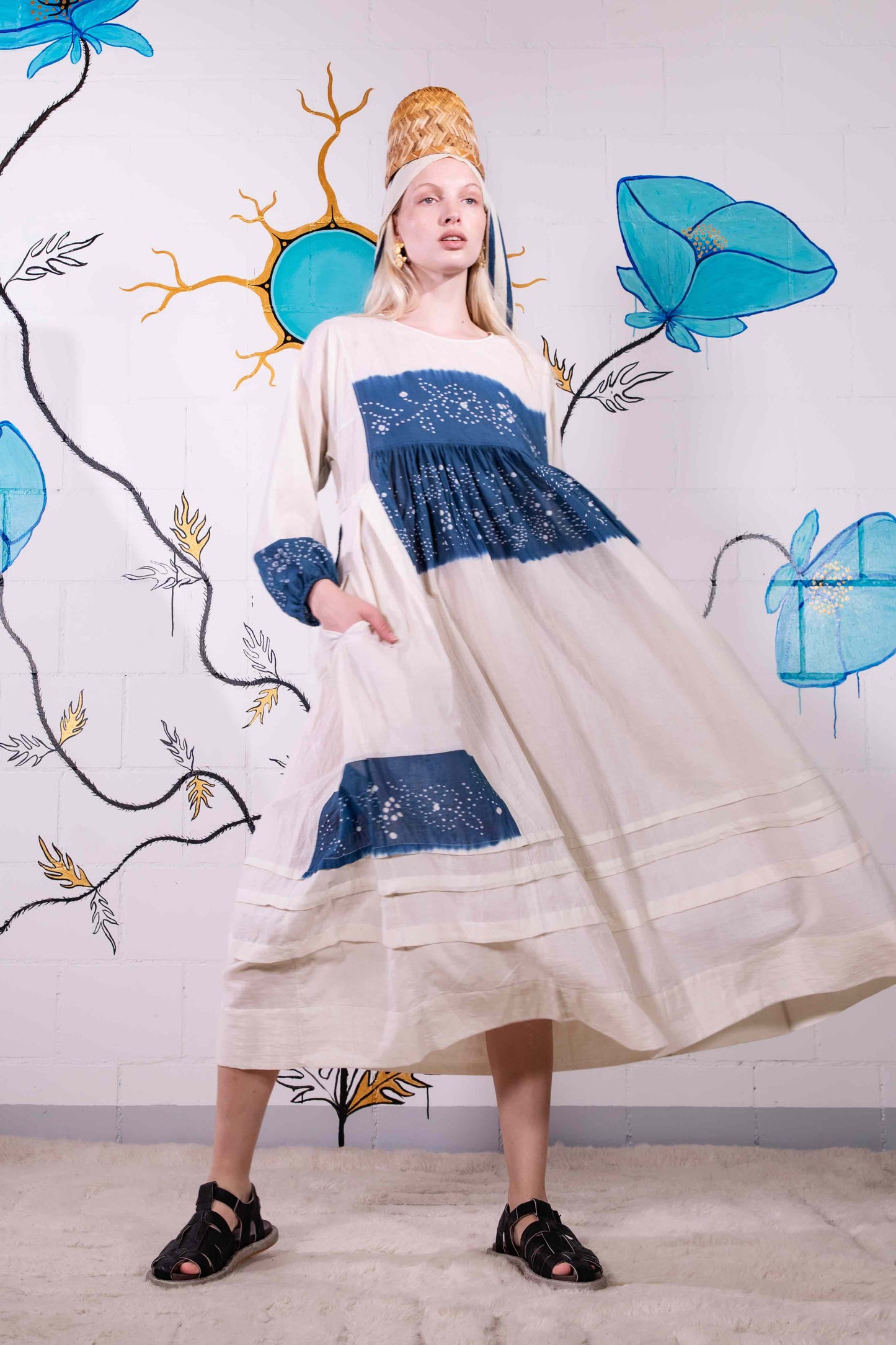 Model wearing pure cotton maxi dress by Injiri – long-sleeve off-white handloomed dress with indigo tie-dye and shibori print, side pockets, and fluid silhouette. Handcrafted in India using organic cotton.