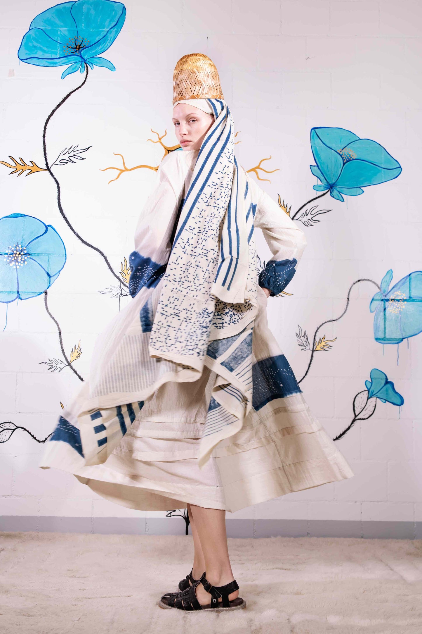 Model wearing pure cotton maxi dress by Injiri – long-sleeve off-white handloomed dress with indigo tie-dye and shibori print, side pockets, and fluid silhouette. Handcrafted in India using organic cotton.
