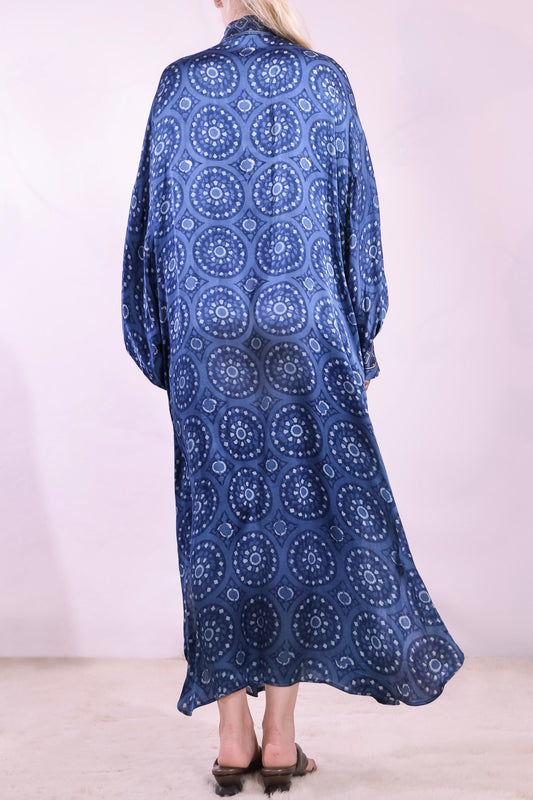 Model wearing Blue Circles Marion Silk Dress by Obidi. Handprinted silk maxi dress with V-neckline, natural indigo Ajrakh blockprint, side pockets, and fluid silhouette. Ethically made in India using traditional techniques.