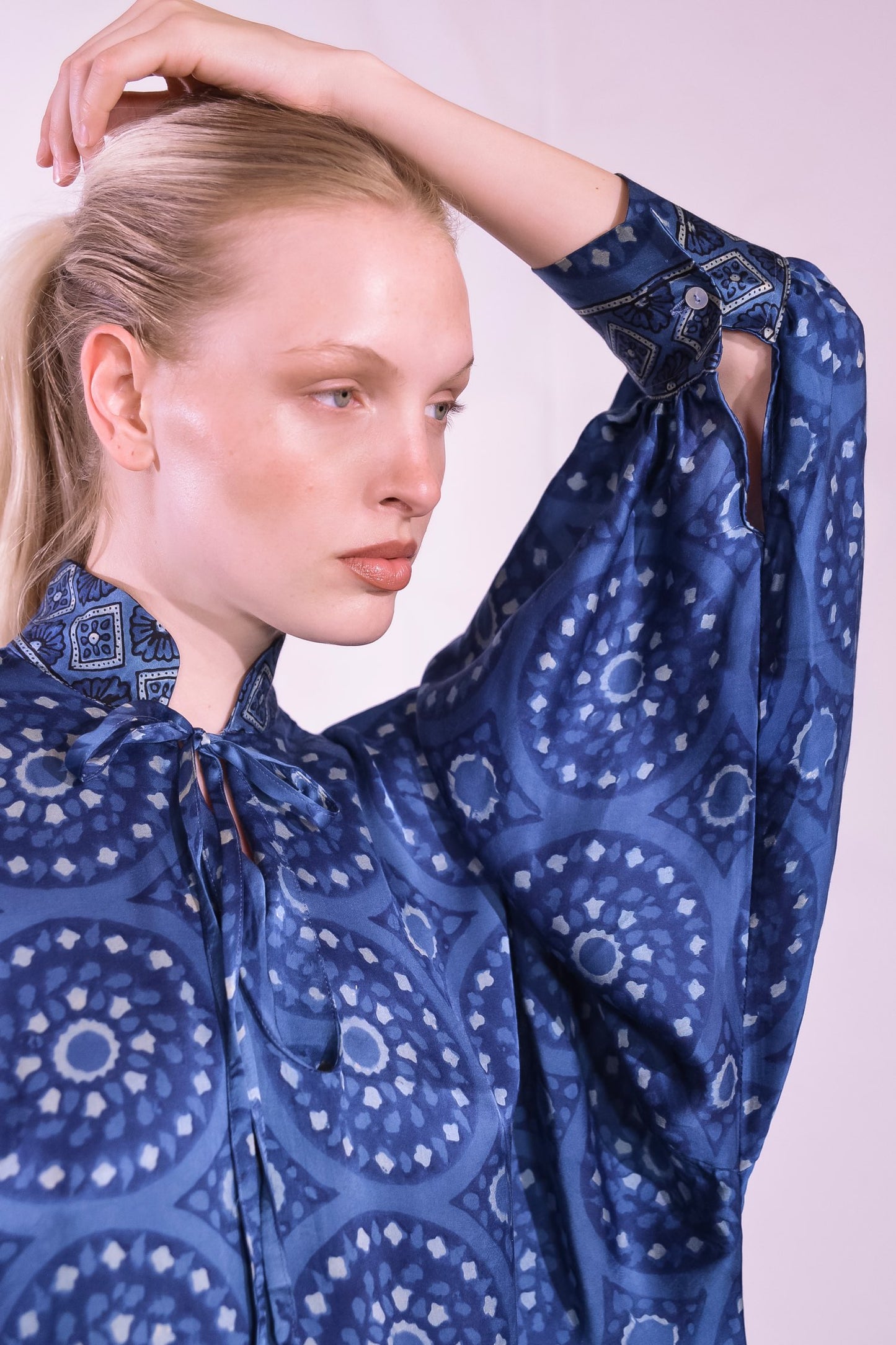 Model wearing Blue Circles Marion Silk Dress by Obidi. Handprinted silk maxi dress with V-neckline, natural indigo Ajrakh blockprint, side pockets, and fluid silhouette. Ethically made in India using traditional techniques.