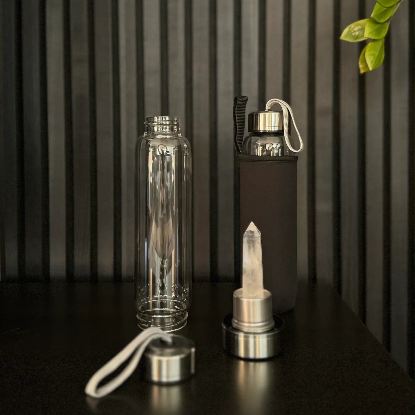 Clear Quartz Crystal Water Bottle by The Goddess Collective, featuring a natural crystal obelisk inside a glass bottle with stainless steel lids and carry sleeve.