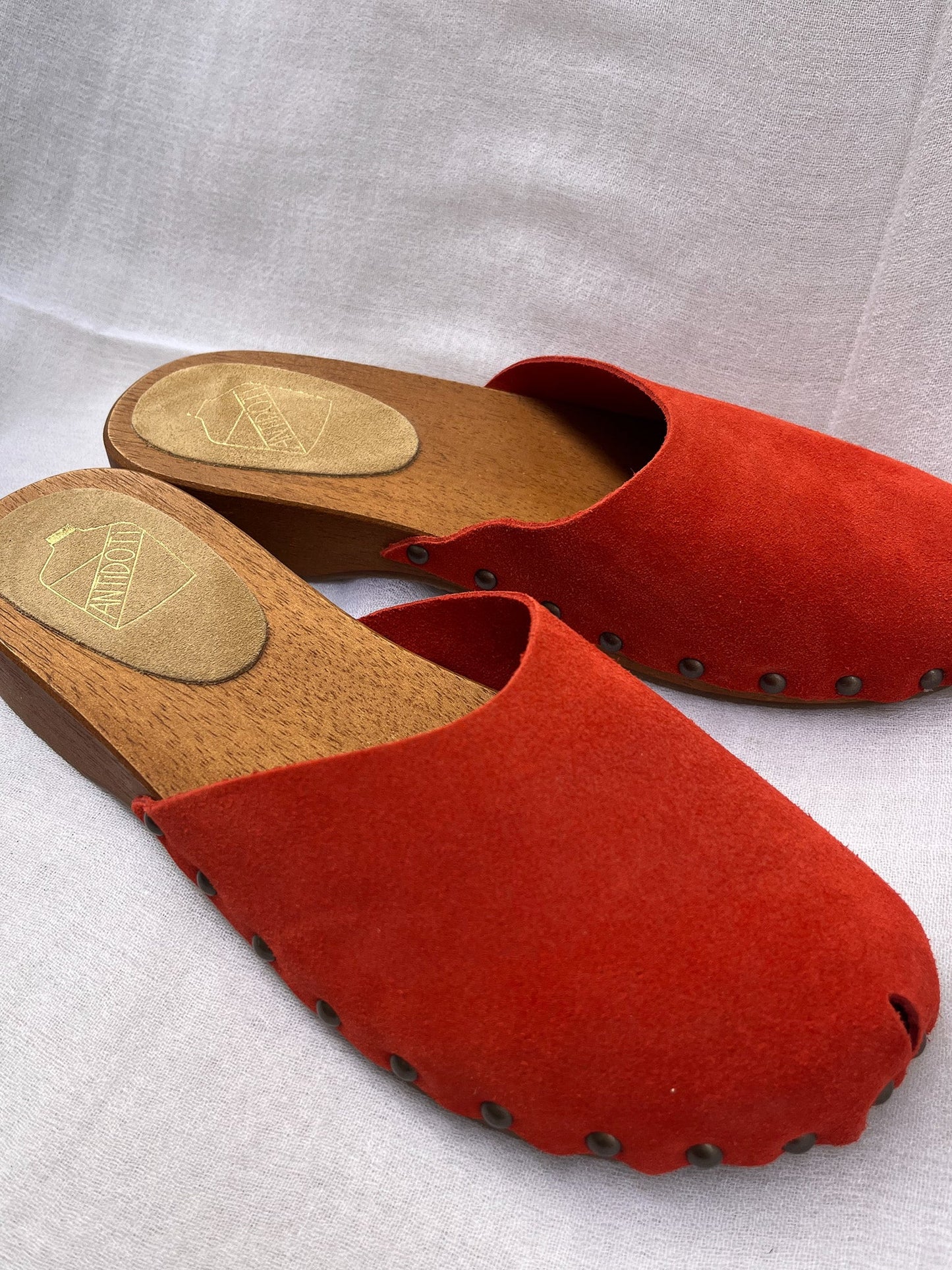 Handmade candy red clogs by Antidoti with studded sides and wooden sole, crafted in Florence, Italy. Available at House of Woven Stories.