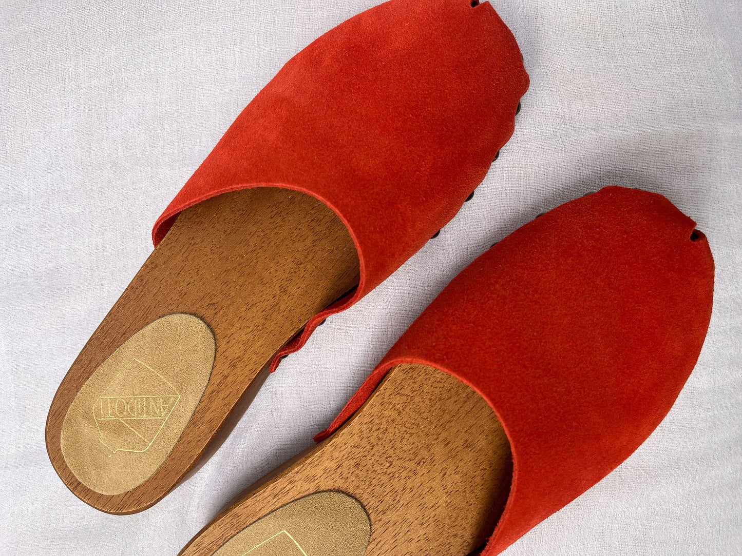 Handmade candy red clogs by Antidoti with studded sides and wooden sole, crafted in Florence, Italy. Available at House of Woven Stories.