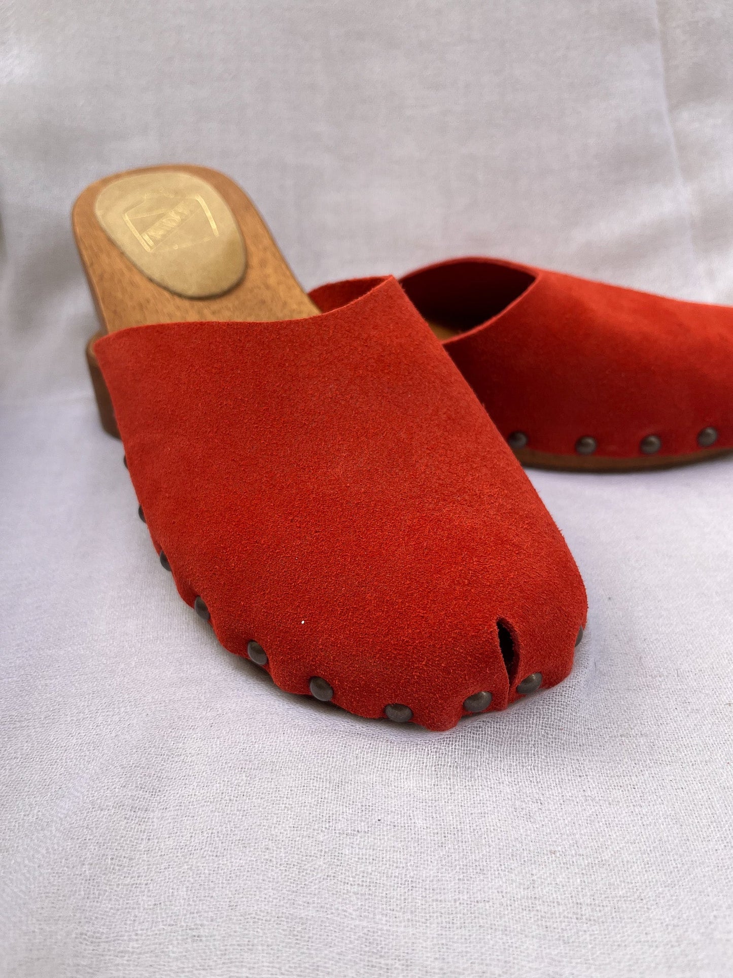 Handmade candy red clogs by Antidoti with studded sides and wooden sole, crafted in Florence, Italy. Available at House of Woven Stories.