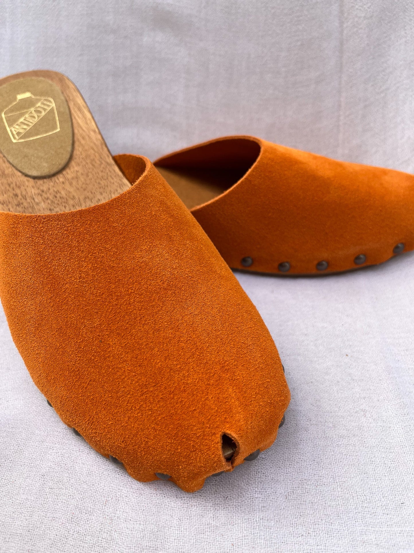 Handmade tangerine velvet clogs by Antidoti with studded sides and wooden sole, crafted in Florence, Italy. Available at House of Woven Stories.