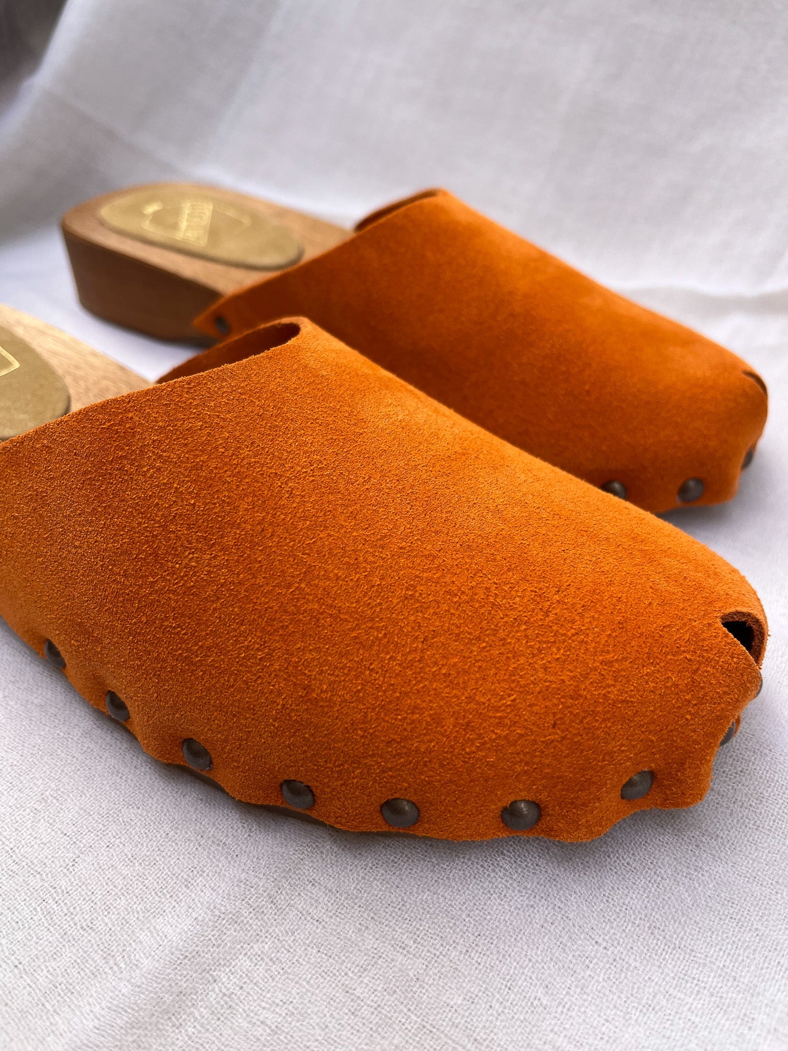Handmade tangerine velvet clogs by Antidoti with studded sides and wooden sole, crafted in Florence, Italy. Available at House of Woven Stories.