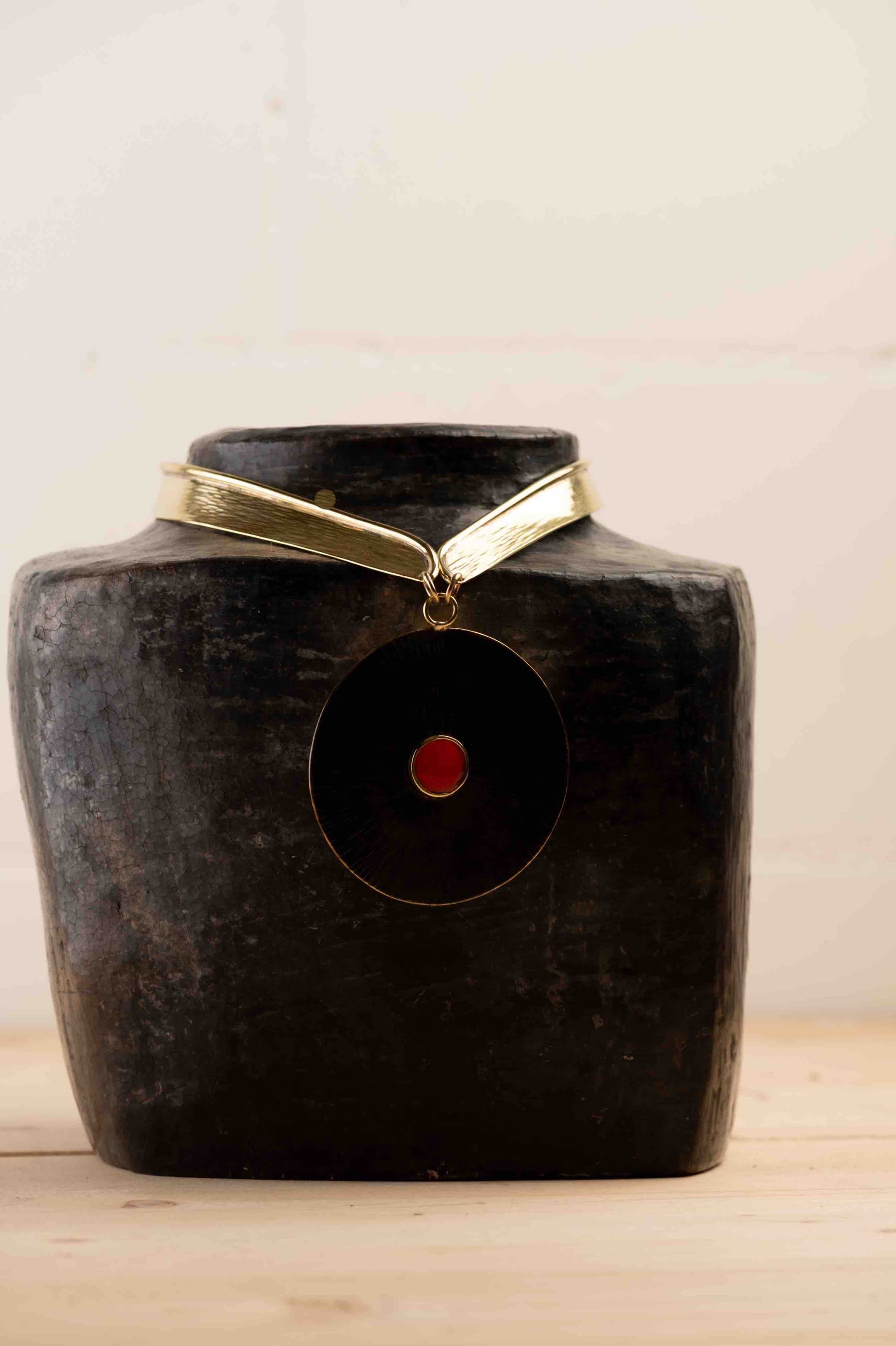 Collier Lacet necklace by Stéphane Szendy, handcrafted hammered bronze with coral-colored geometric enamel pendant, blending traditional craftsmanship with contemporary design. Part of House of Woven Stories selection.