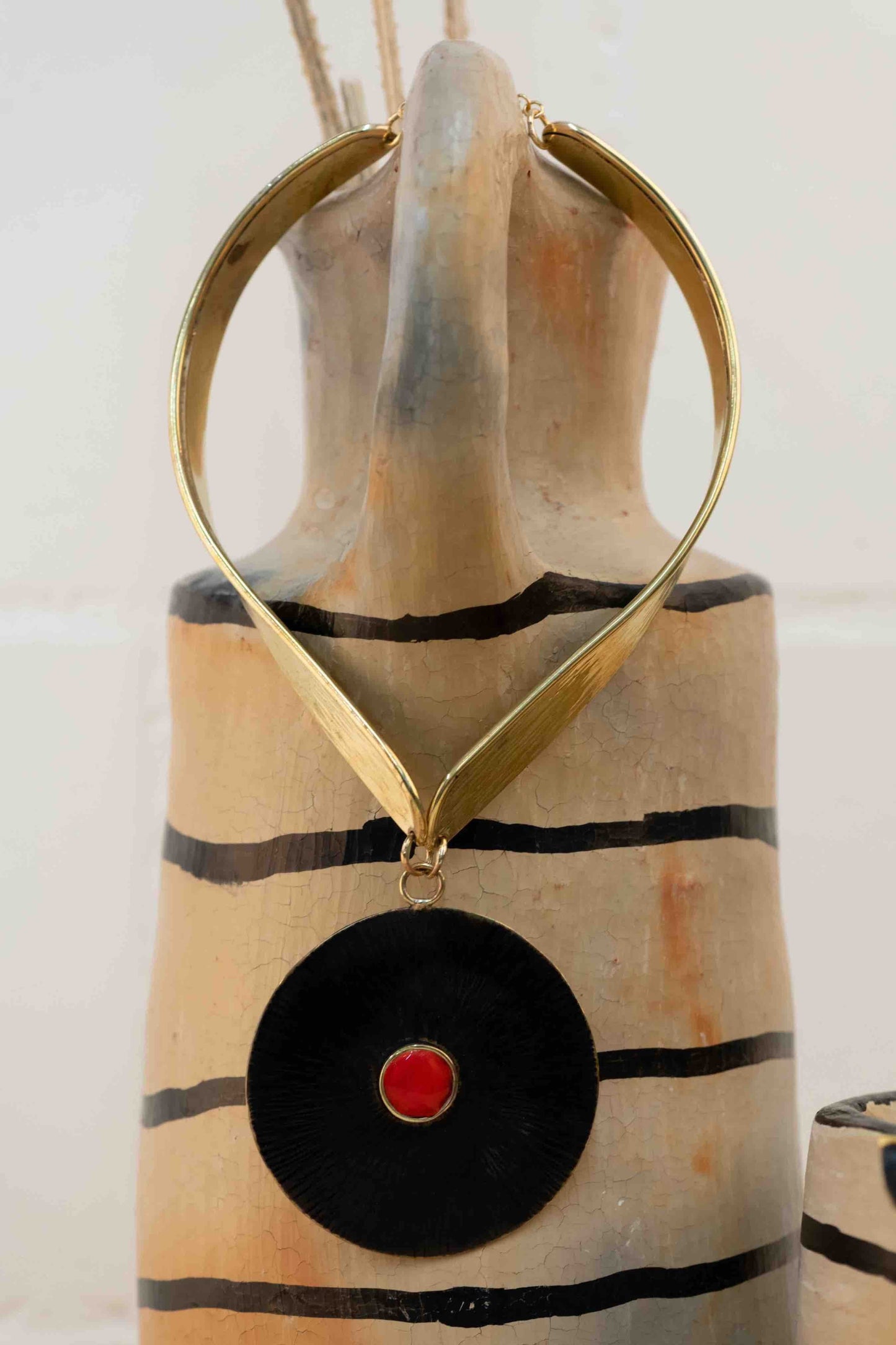 Collier Lacet necklace by Stéphane Szendy, handcrafted hammered bronze with coral-colored geometric enamel pendant, blending traditional craftsmanship with contemporary design. Part of House of Woven Stories selection.
