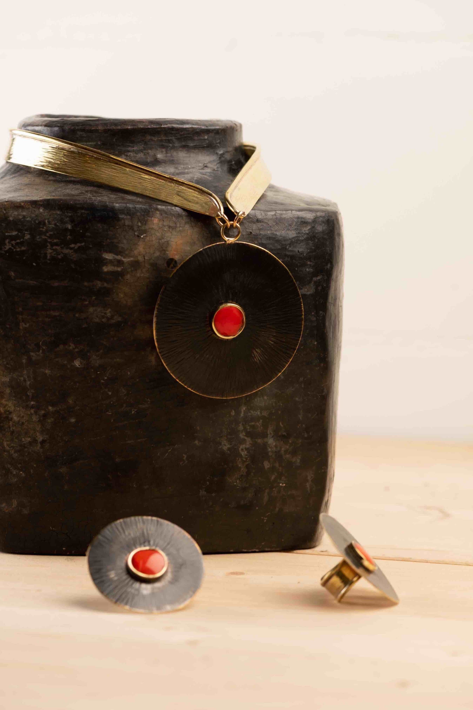 Collier Lacet necklace by Stéphane Szendy, handcrafted hammered bronze with coral-colored geometric enamel pendant, blending traditional craftsmanship with contemporary design. Part of House of Woven Stories selection.