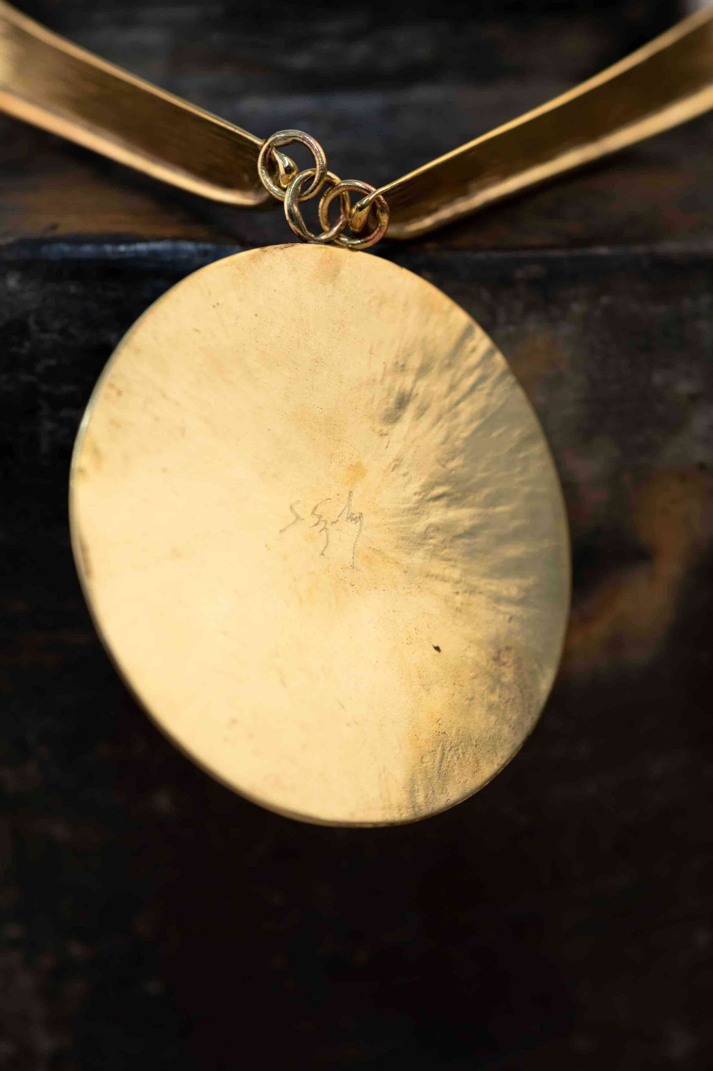 Collier Lacet necklace by Stéphane Szendy, handcrafted hammered bronze with coral-colored geometric enamel pendant, blending traditional craftsmanship with contemporary design. Part of House of Woven Stories selection.
