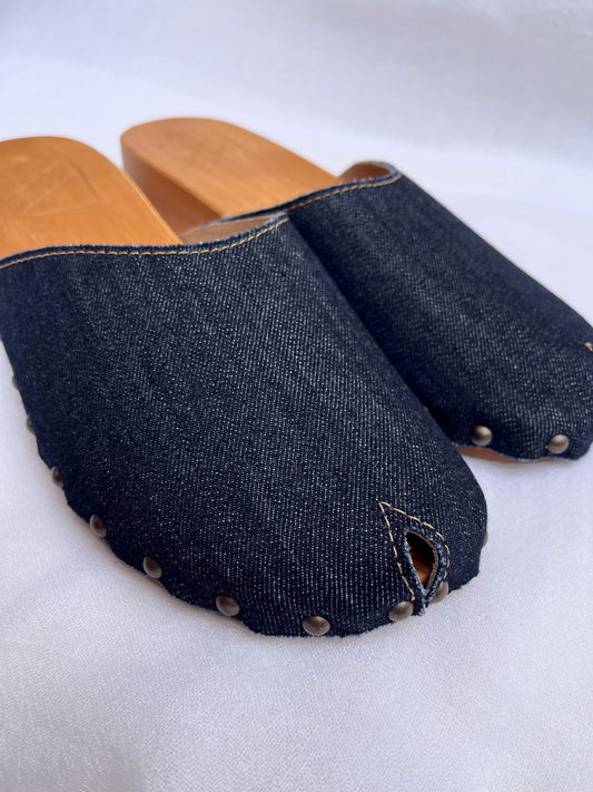 Handmade dark denim clogs by Antidoti with studded sides and wooden sole, crafted in Florence, Italy. Available at House of Woven Stories.