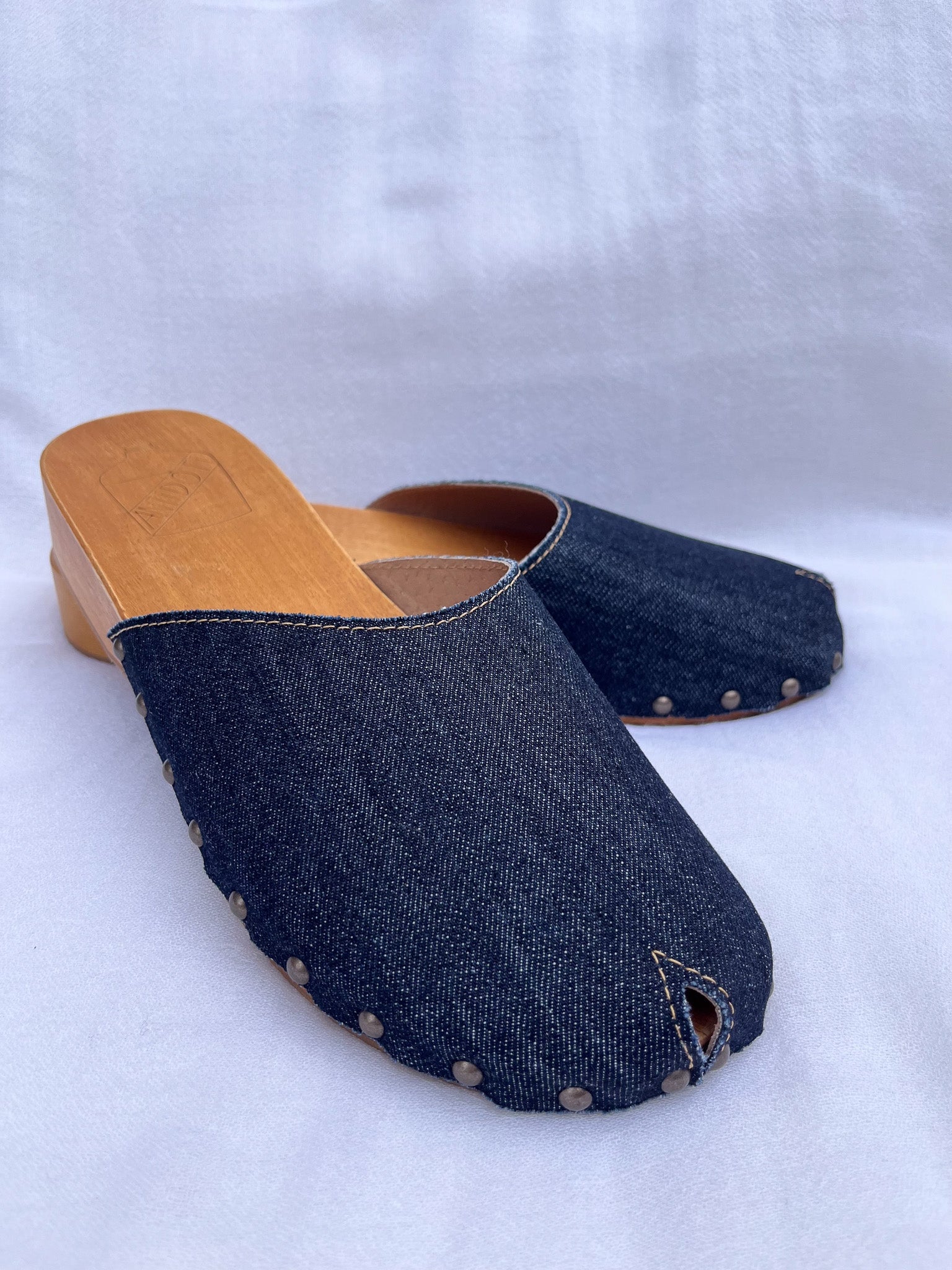 Handmade dark denim clogs by Antidoti with studded sides and wooden sole, crafted in Florence, Italy. Available at House of Woven Stories.