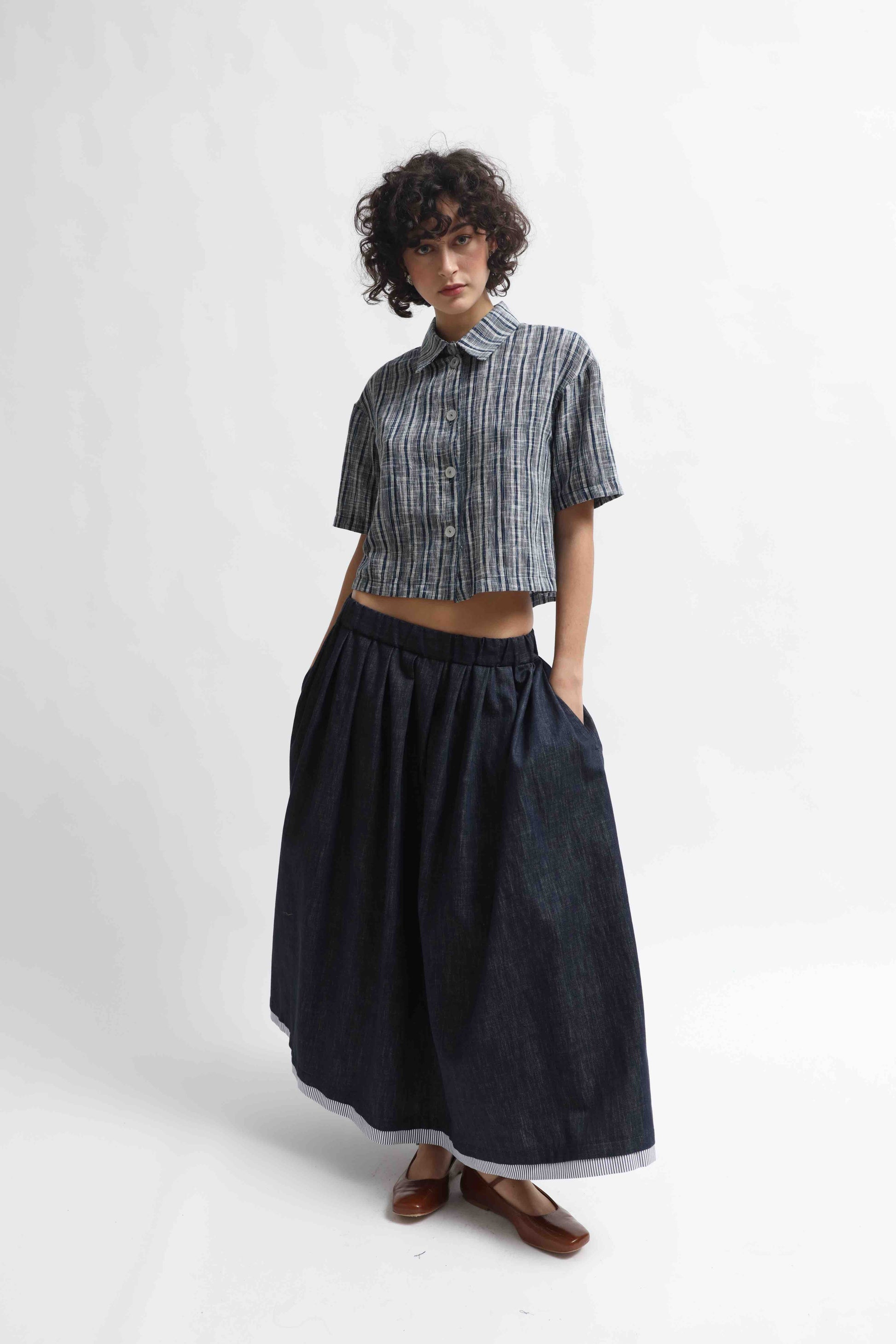 The Emily Shirt is a breathable, lightweight cropped top made from 100% hand-loomed Kala cotton. Available in denim and white, handcrafted in Italy by House of Woven Stories for sustainable, timeless style.