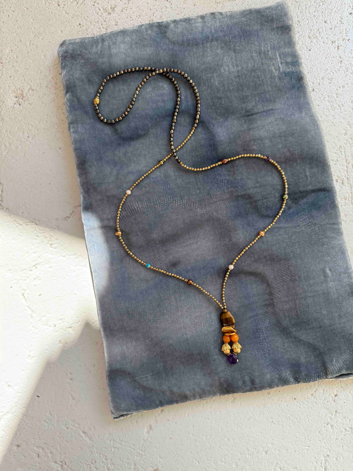 Gold and Tiger’s Eye Totem Pendant choker necklace by Ilaria Fiorentini Jewellery, featuring tiger’s eye, pyrite, turquoise, freshwater pearls, amber resin, natural amethyst, and raw brass details. Handcrafted in Italy, inspired by African and Indonesian artisan traditions. Part of House of Woven Stories selection.