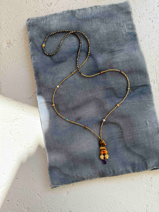 Gold and Tiger’s Eye Totem Pendant choker necklace by Ilaria Fiorentini Jewellery, featuring tiger’s eye, pyrite, turquoise, freshwater pearls, amber resin, natural amethyst, and raw brass details. Handcrafted in Italy, inspired by African and Indonesian artisan traditions. Part of House of Woven Stories selection.