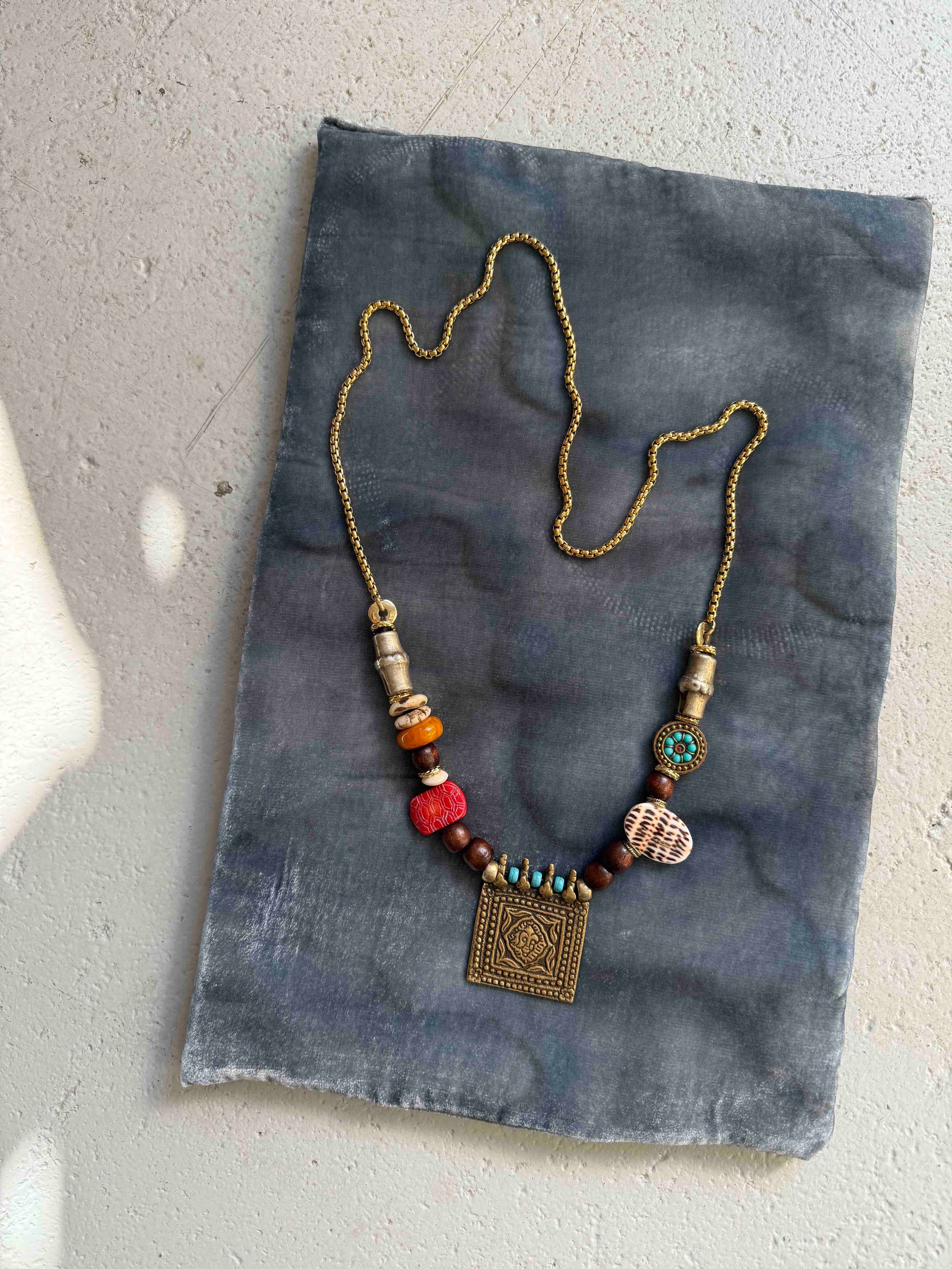Bold handcrafted Urban Tribe Ring Square Necklace by Ilaria Fiorentini Jewellery from the House of Woven Stories selection, featuring red bamboo coral, turquoise paste, amber resin, brass and wooden details, mother-of-pearl accent, and gold-plated steel chain, inspired by African and Indonesian artisans, made in Italy.